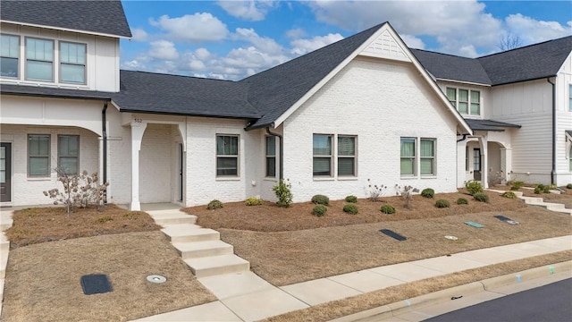 view of front of house with a shingled roof and brick siding