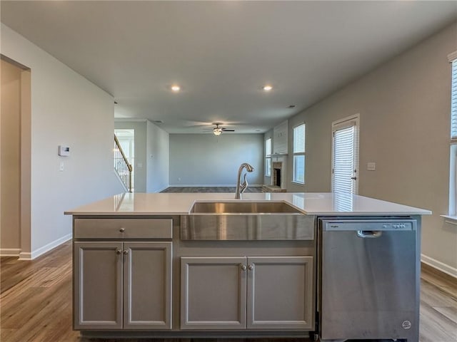 kitchen with a healthy amount of sunlight, open floor plan, gray cabinets, stainless steel dishwasher, and a sink