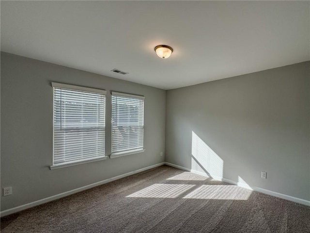 carpeted spare room featuring visible vents and baseboards