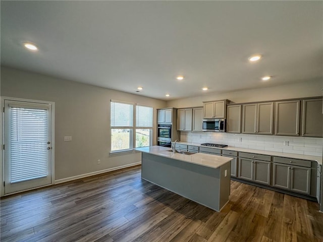 kitchen featuring tasteful backsplash, appliances with stainless steel finishes, gray cabinetry, and dark wood-style flooring