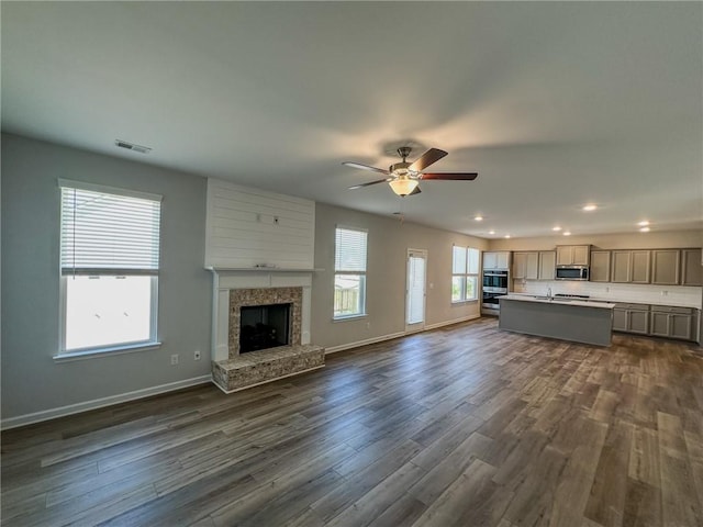 unfurnished living room featuring baseboards, dark wood-style floors, visible vents, and a premium fireplace