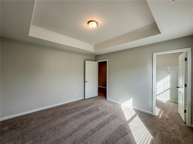 unfurnished bedroom featuring a tray ceiling, baseboards, carpet floors, and ornamental molding