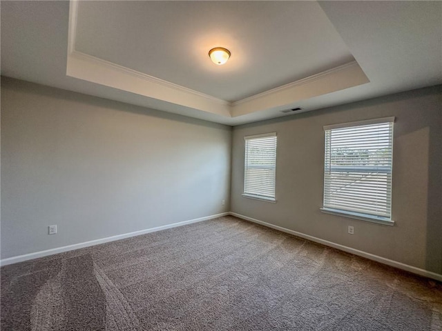 carpeted spare room with visible vents, crown molding, a raised ceiling, and baseboards