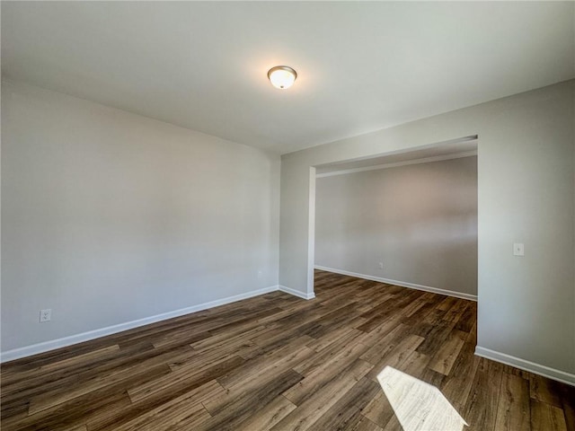 unfurnished room with baseboards and dark wood-style flooring