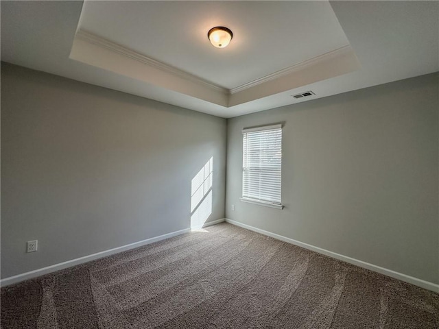 empty room featuring a raised ceiling, carpet flooring, crown molding, and baseboards