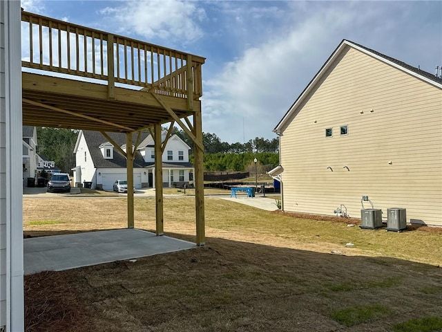 view of yard with central AC unit, a wooden deck, and a patio