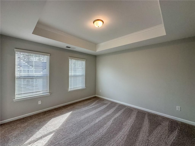 unfurnished room featuring a tray ceiling, baseboards, and visible vents