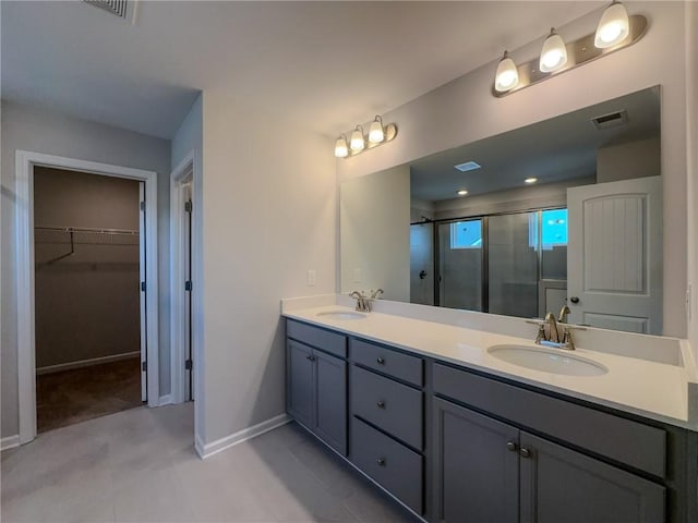 bathroom featuring double vanity, visible vents, a shower stall, and a sink