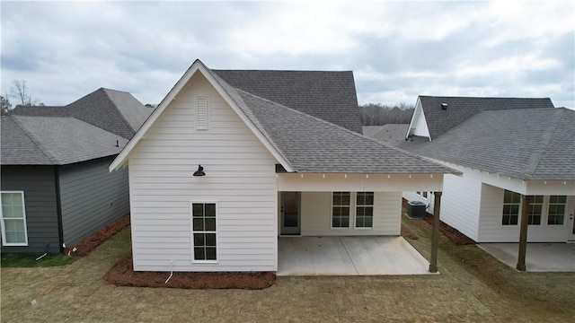 rear view of house with central air condition unit, a patio, and a shingled roof