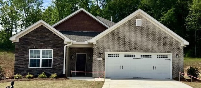 view of front facade with an attached garage, driveway, roof with shingles, and stone siding