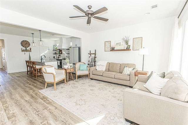 living room featuring sink, ceiling fan, and light hardwood / wood-style floors