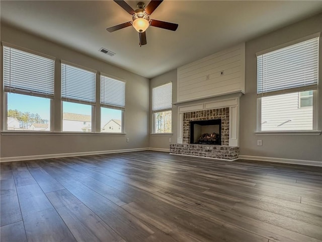 unfurnished living room featuring ceiling fan, a fireplace, and dark hardwood / wood-style floors