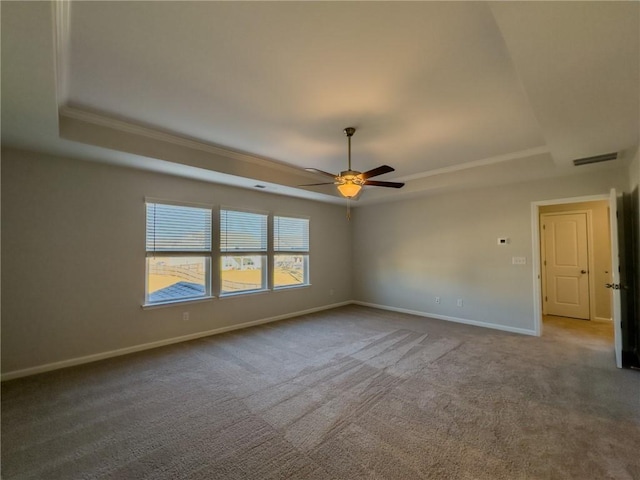 carpeted spare room featuring ceiling fan and a raised ceiling