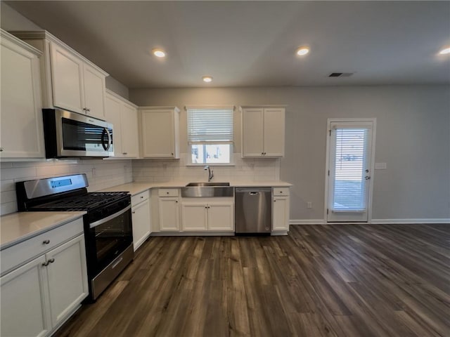 kitchen with white cabinetry, stainless steel appliances, backsplash, dark wood-type flooring, and sink