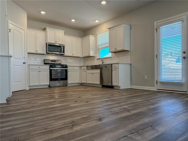 kitchen featuring backsplash, appliances with stainless steel finishes, dark hardwood / wood-style flooring, and white cabinetry