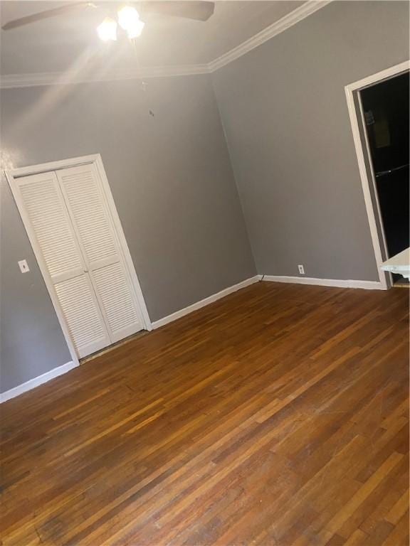 unfurnished bedroom featuring ceiling fan, dark hardwood / wood-style floors, ornamental molding, and a closet