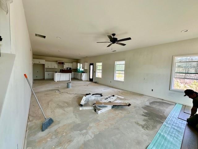 unfurnished living room with visible vents and a ceiling fan