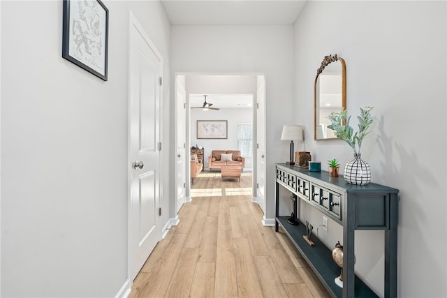 corridor with baseboards and light wood-style floors