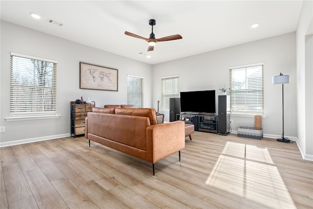 living area featuring a wealth of natural light, visible vents, a ceiling fan, and light wood finished floors