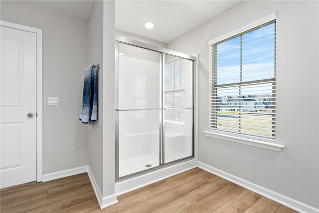 bathroom featuring baseboards, wood finished floors, and a stall shower