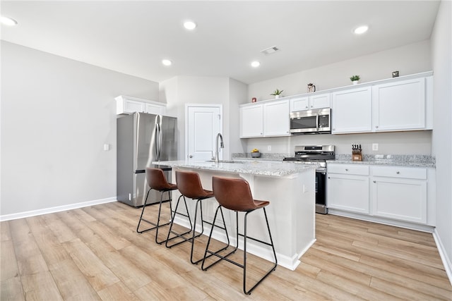 kitchen with visible vents, light wood-style flooring, a kitchen breakfast bar, stainless steel appliances, and a sink