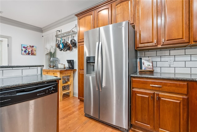 kitchen featuring crown molding, dark stone countertops, tasteful backsplash, light hardwood / wood-style floors, and stainless steel appliances