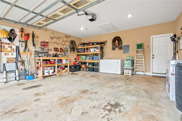 garage with a workshop area, electric panel, a garage door opener, and white refrigerator