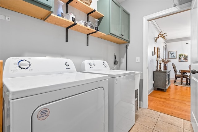 clothes washing area featuring cabinets, independent washer and dryer, and light tile patterned flooring