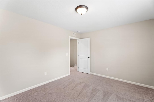 empty room with baseboards, light colored carpet, and visible vents