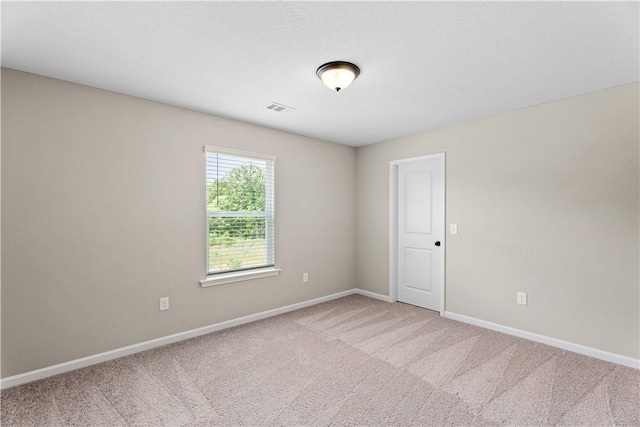 spare room with baseboards, carpet flooring, and visible vents