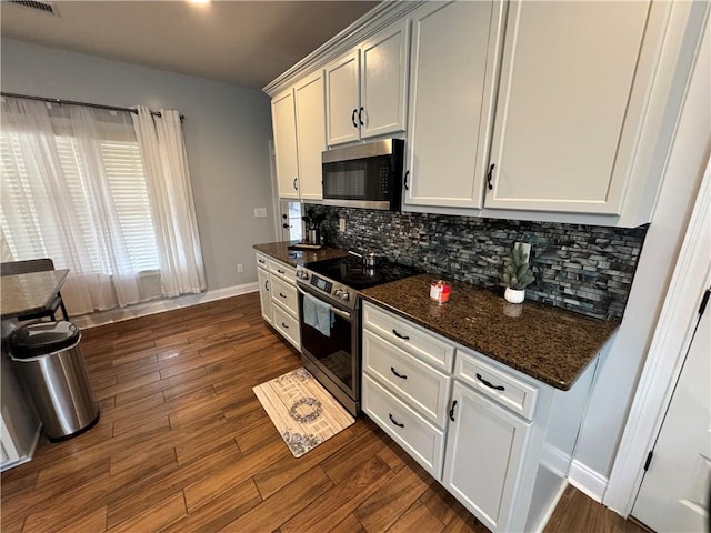 kitchen featuring stainless steel appliances, white cabinets, and dark stone counters