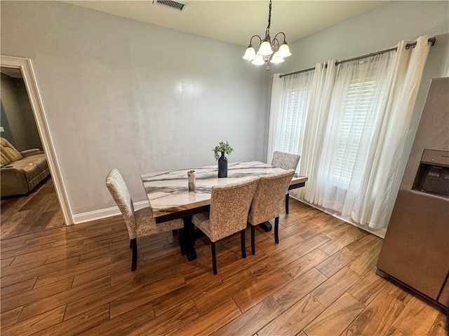 dining space with hardwood / wood-style floors and a notable chandelier