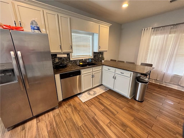 kitchen featuring stainless steel appliances, kitchen peninsula, sink, and light wood-type flooring