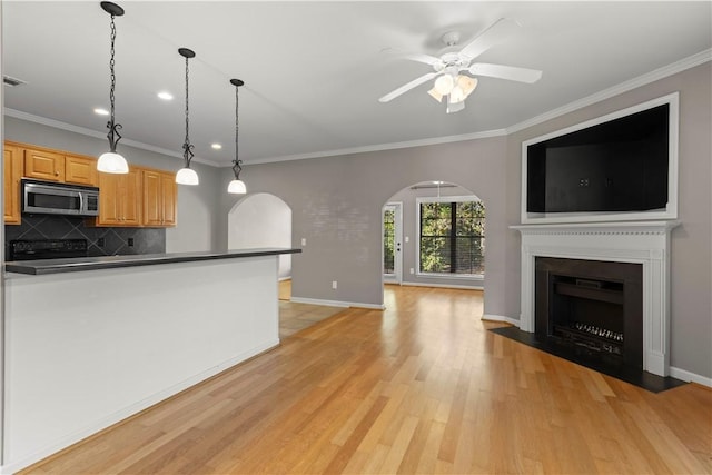 kitchen with decorative backsplash, ornamental molding, ceiling fan, pendant lighting, and light hardwood / wood-style floors