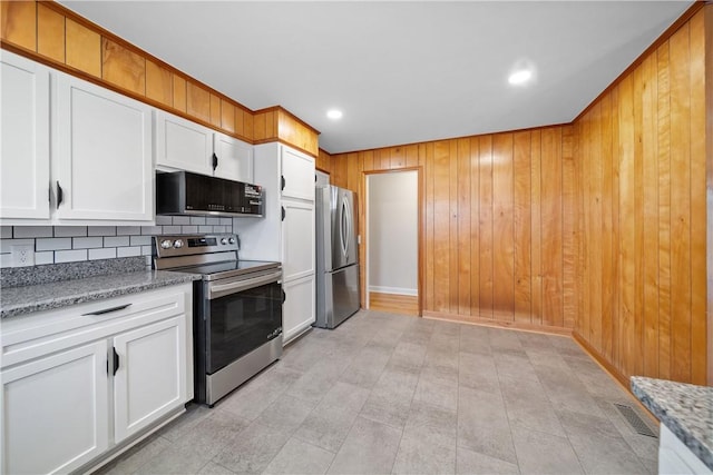 kitchen featuring light stone counters, stainless steel appliances, visible vents, white cabinets, and tasteful backsplash