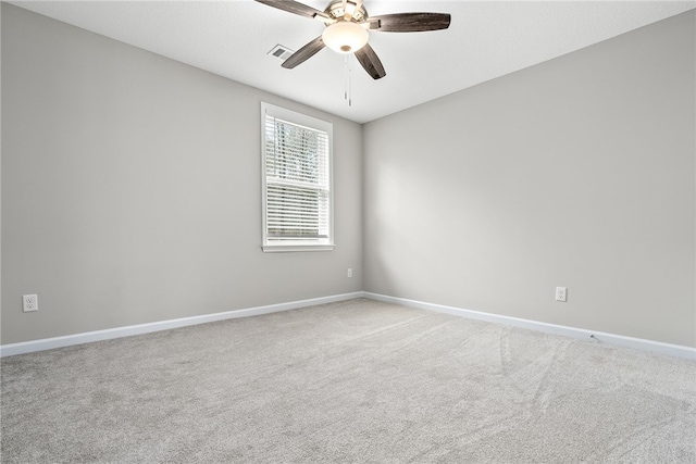 carpeted spare room featuring a ceiling fan, visible vents, and baseboards