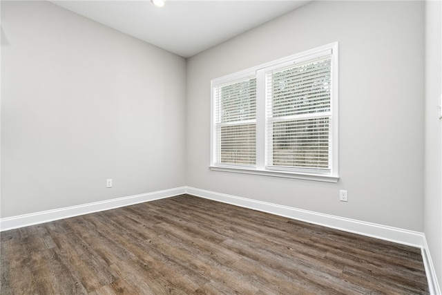 unfurnished room with dark wood-type flooring and baseboards