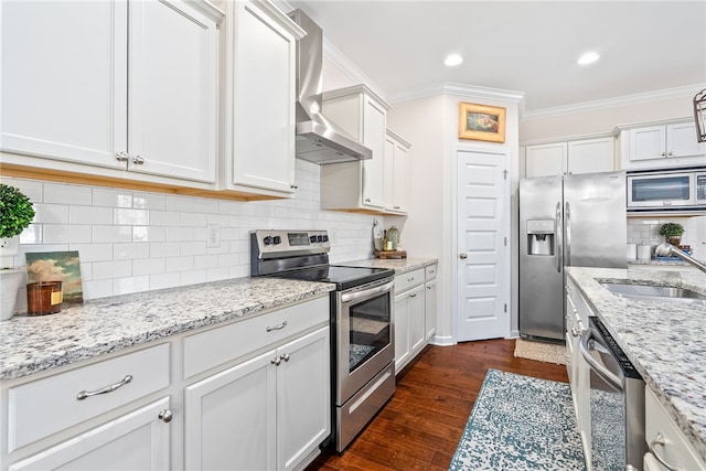 kitchen featuring crown molding, dark wood-style flooring, wall chimney exhaust hood, white cabinets, and appliances with stainless steel finishes
