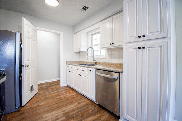 kitchen with sink, dark wood-type flooring, stainless steel appliances, tasteful backsplash, and white cabinets