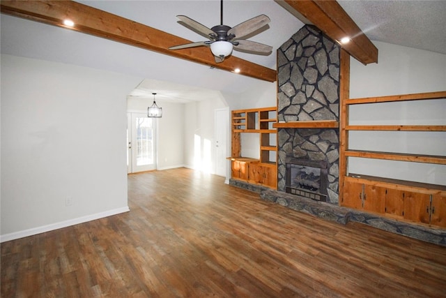 unfurnished living room with ceiling fan, a fireplace, lofted ceiling with beams, and hardwood / wood-style flooring