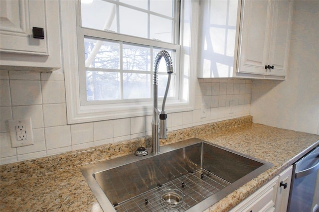 interior details with light stone countertops, decorative backsplash, white cabinetry, and sink