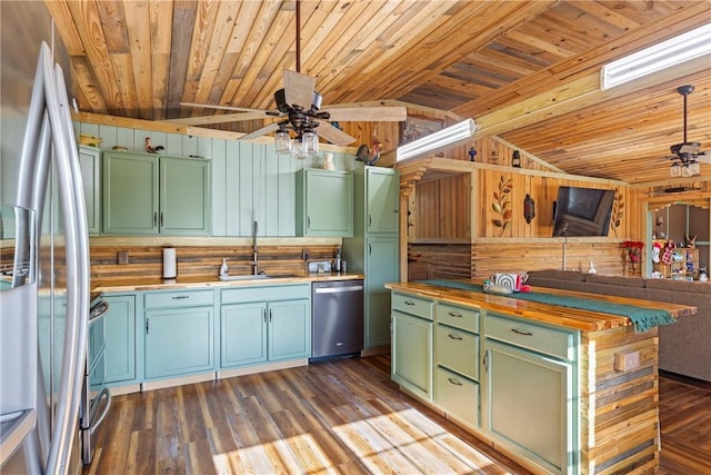 kitchen featuring butcher block counters, ceiling fan, stainless steel appliances, green cabinets, and wood walls