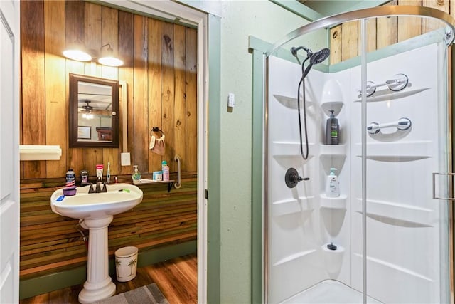 bathroom with a shower with door and wood walls