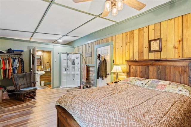 bedroom with hardwood / wood-style floors, a closet, wooden walls, and ceiling fan