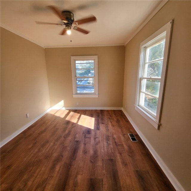 empty room featuring dark hardwood / wood-style flooring, a wealth of natural light, ornamental molding, and ceiling fan