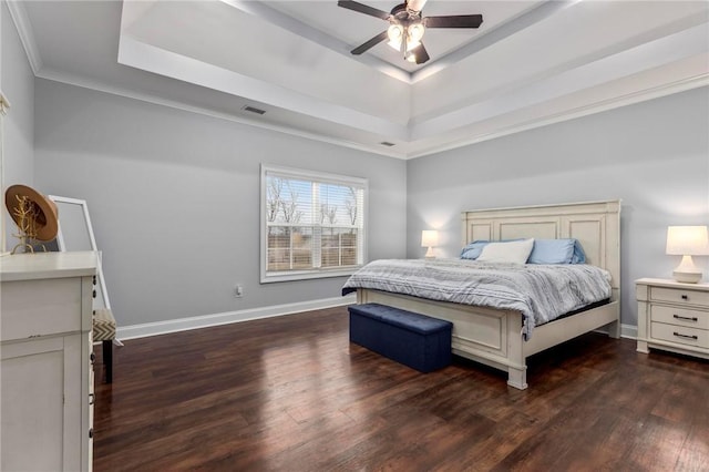 bedroom with dark wood-type flooring, ceiling fan, ornamental molding, and a raised ceiling