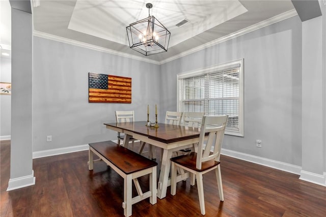 dining space featuring dark hardwood / wood-style floors, a tray ceiling, a chandelier, and ornamental molding