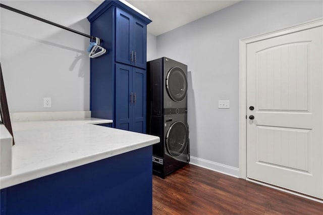 laundry area with dark wood-type flooring, cabinets, and stacked washer / dryer