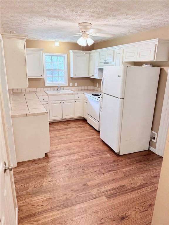 460 Waverly Rd, Auburn, AL 36832 - kitchen featuring white appliances, tile counters, ceiling fan, light wood finished floors, and white cabinetry