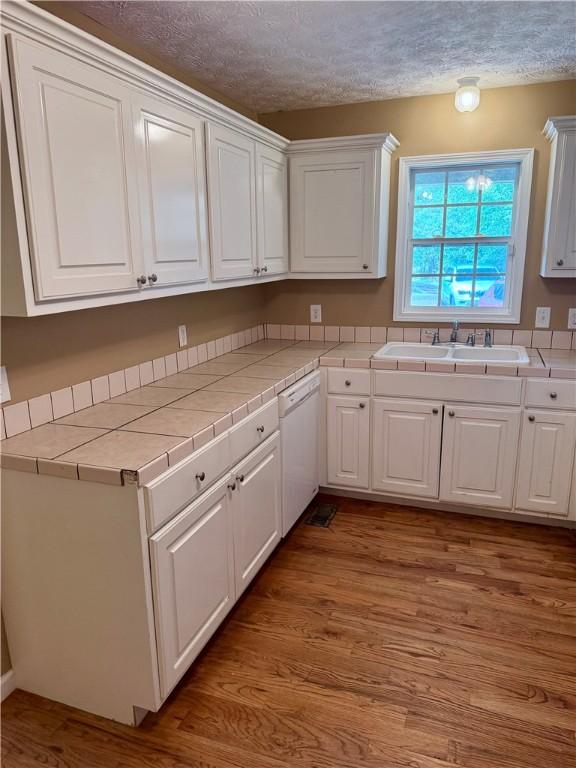 460 Waverly Rd, Auburn, AL 36832 - kitchen with tile counters, white cabinetry, white dishwasher, light wood finished floors, and a textured ceiling